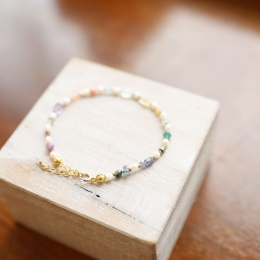 Delikatna bransoletka z perłą i hematytem, wykonana na przezroczystej żyłce ze złoconym srebrnym zapięciem.