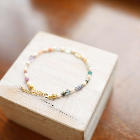 Bransoletka na żyłce jubilerskiej z ozdobiona perłą oraz kamieniami naturalnymi: ametystem, granatem, opalem i kwarcem.