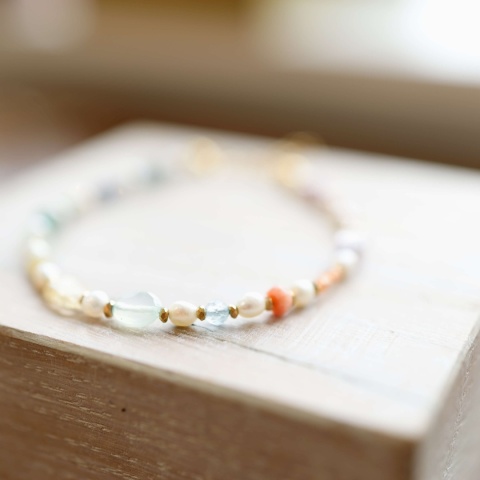 Elegancka bransoletka z różnorodnymi kamieniami naturalnymi, takimi jak iolit, granat i opal, ozdobiona złotymi detalami.