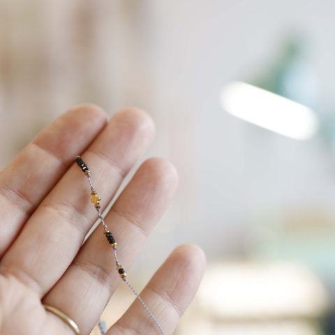 Zbliżenie na kamień czarnego turmalinu w bransoletce z delikatnym złotym wykończeniem na tle dłoni