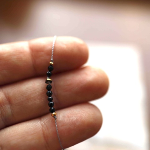 Zbliżenie na kamień czarnego turmalinu w bransoletce z delikatnym złotym wykończeniemz hematytu.