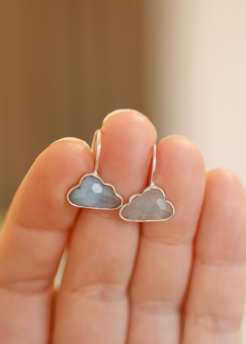 Srebrne kolczyki chmurki trzymane w palcach, zdjęcie prezentacyjne