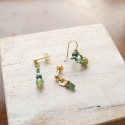 Zestaw trzech różnych kolczyków z serii „Pary nie do pary”, z elementami z zielonych kamieni i złotymi detalami.