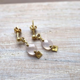 Zbliżenie na eleganckie kolczyki z różowym kwarcem i matową, kwadratową blaszką w kolorze złota.