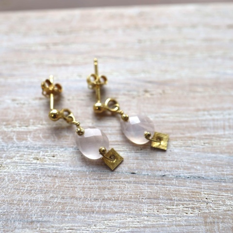 Zbliżenie na eleganckie kolczyki z różowym kwarcem i matową, kwadratową blaszką w kolorze złota.