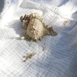 Naszyjnik wykonany na nylonowej nici z naturalnymi kameniami leżący na muszli