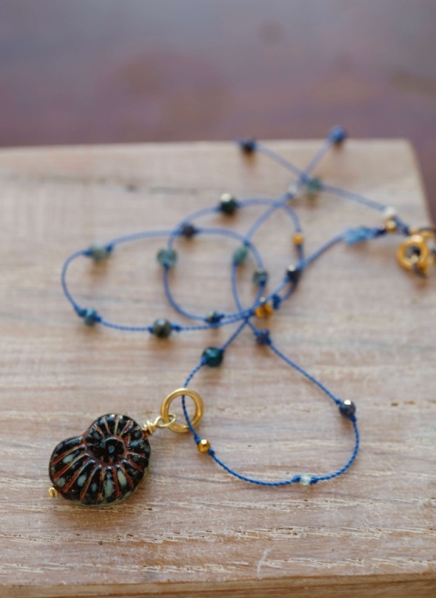 Granatowy delikatny naszyjnik na jasnym tle.