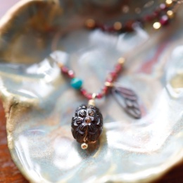 Biżuteria handmade z granatem, opalem i rzeźbioną zawieszką, ułożona w miseczce