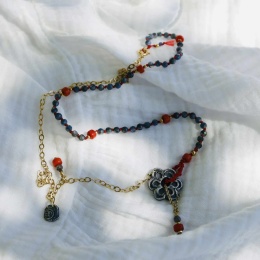 Ręcznie wykonany naszyjnik z kianitu, koralu i pozłacanego srebra na białym tle.