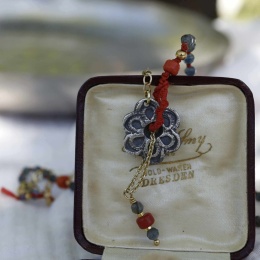 Zbilżenie na artystyczny naszyjnik z kwiatowym medalionem i kolorowymi kamieniami.