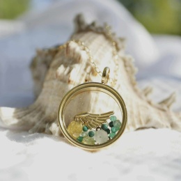 Biżuteria z medalionem wypełnionym kamieniami i złotym skrzydłem.